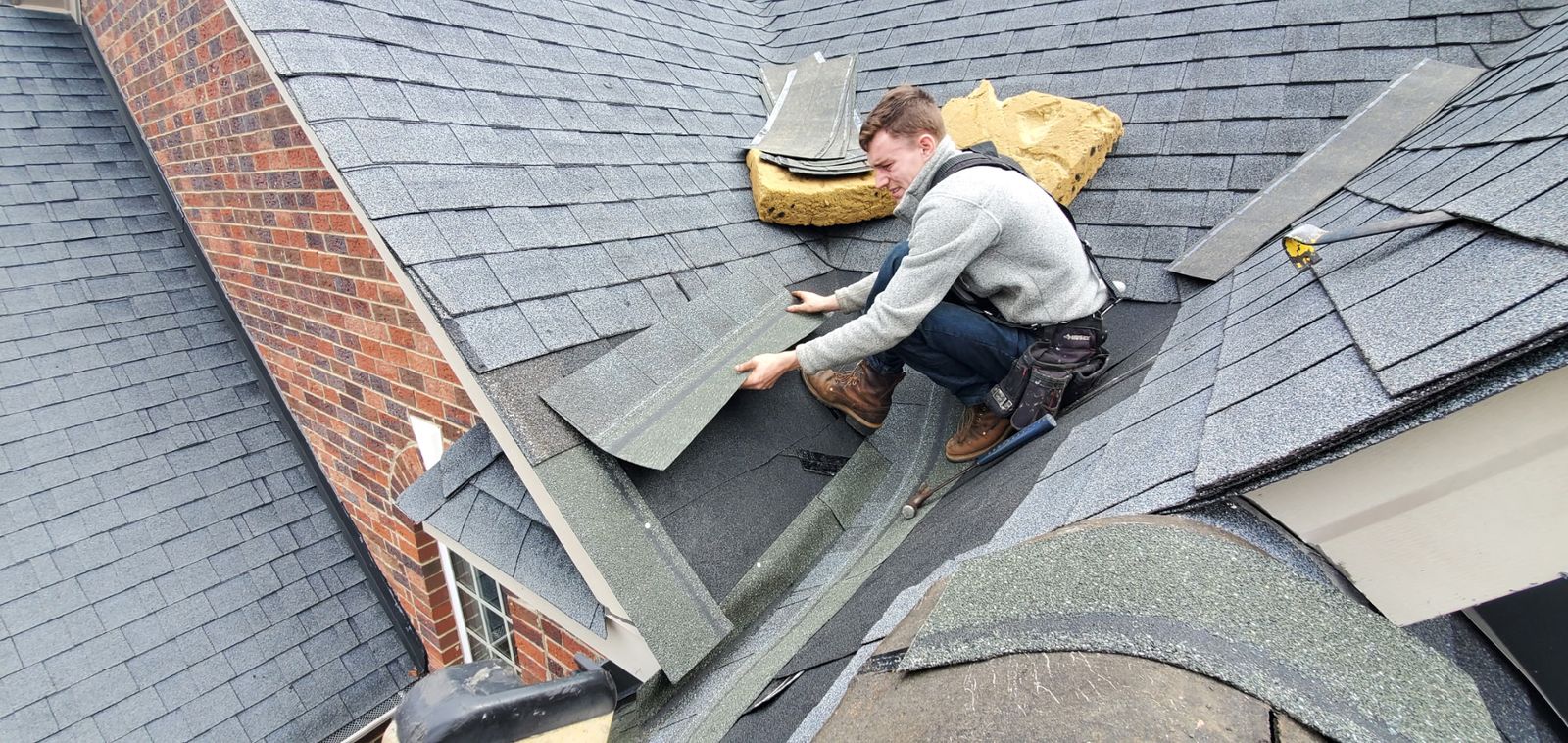 Roofer inspecting shingle damage